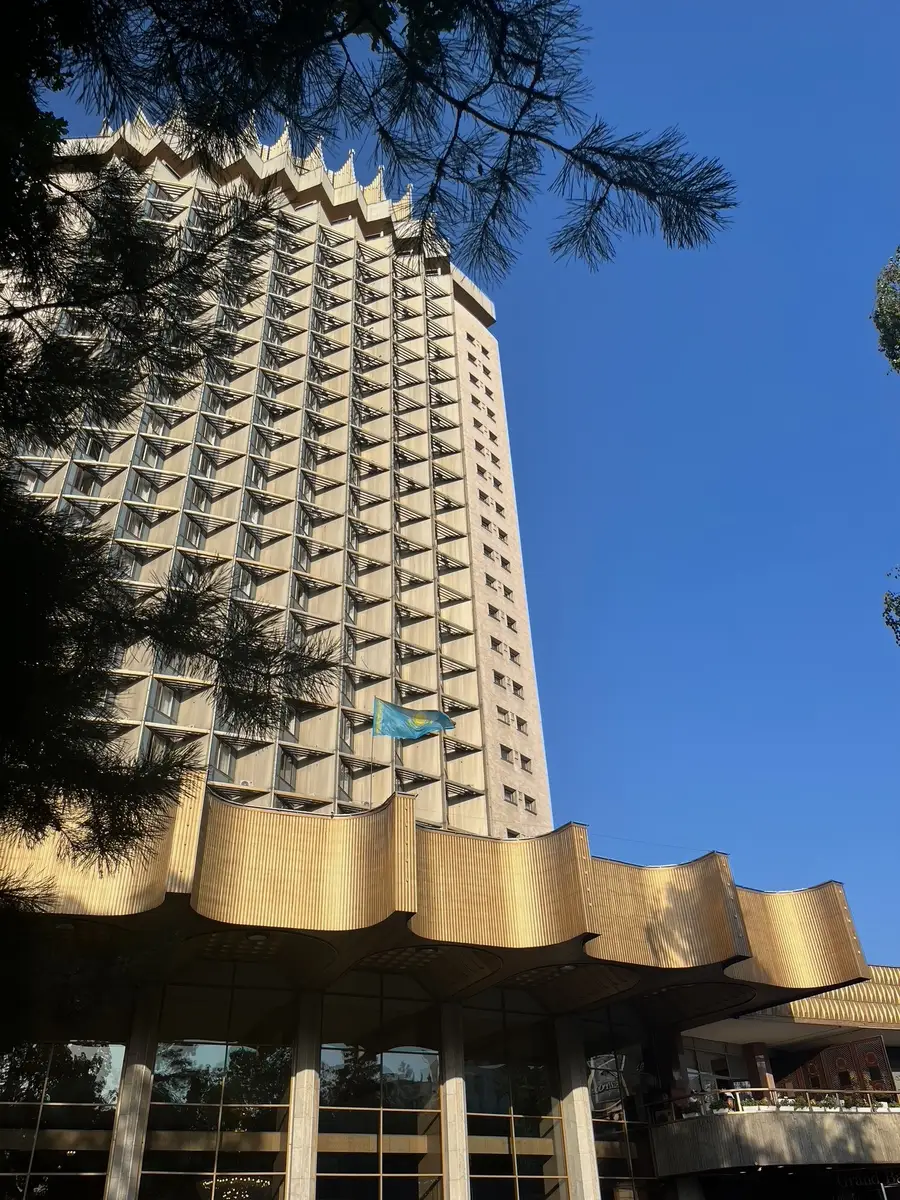 The distinctive crown-topped 'Kazakhstan' hotel high-rise in Almaty with the national flag on its facade